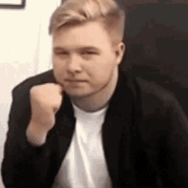 a man in a black jacket and white shirt is making a funny face .