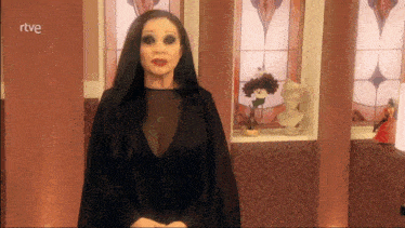 a woman in a black dress stands in front of a stained glass window with rtve written on the bottom right