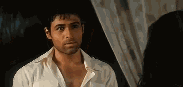a man in a white shirt is looking at a woman in a room .