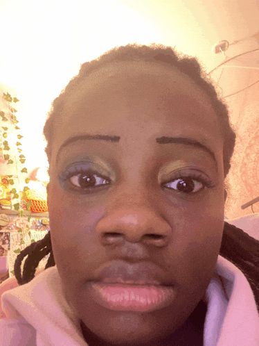 a close up of a woman 's face with a pink sweatshirt on