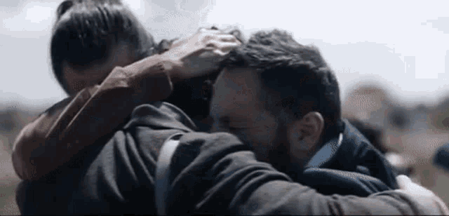 a man and a woman are hugging each other .