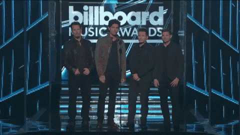 a group of men are standing on a stage with a microphone