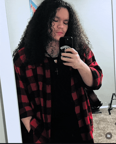 a man with long curly hair is taking a selfie
