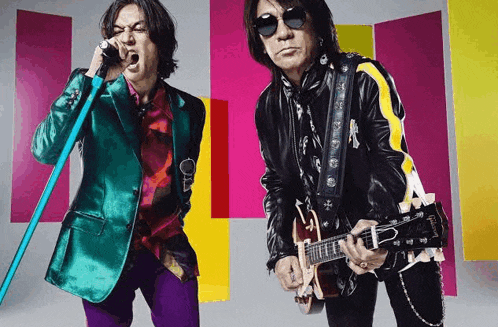 a man in a colorful suit is singing into a microphone while another man is playing a guitar .