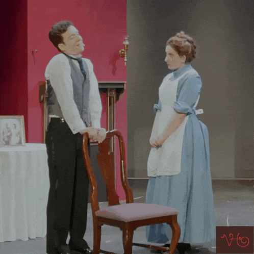a woman in a blue dress stands next to a man in a black suit