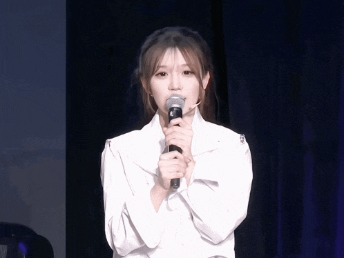 a girl in a white shirt is holding a microphone with the letter s on it