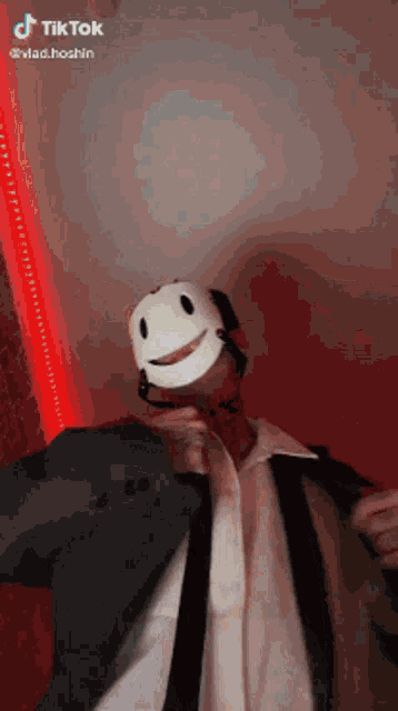 a man in a suit and tie is wearing a mask with a smile on it .