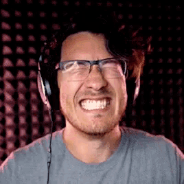 a man wearing glasses and headphones is smiling and making a face .
