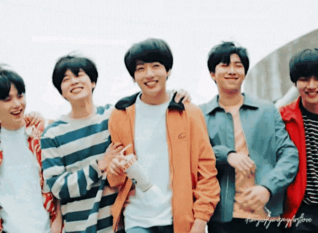 a group of young men are standing next to each other smiling .