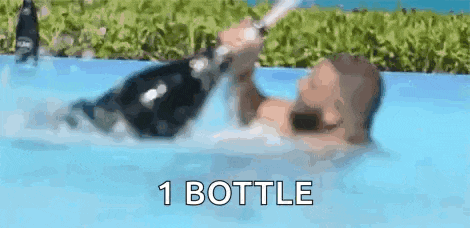 a man is swimming in a pool with a bottle of champagne in his hand .