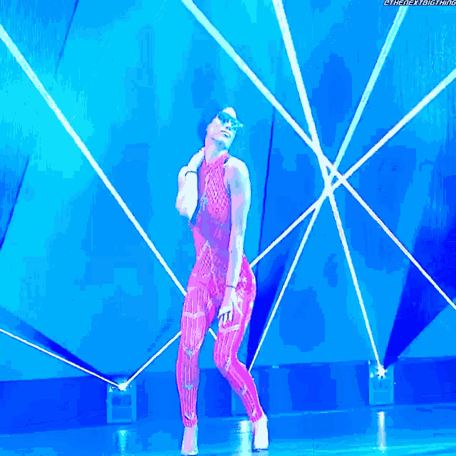 a woman in a pink bodysuit is dancing in front of a blue background that says thenextbig thing