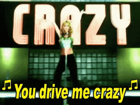 a woman is standing in front of a sign that says `` you drive me crazy '' while holding a microphone .