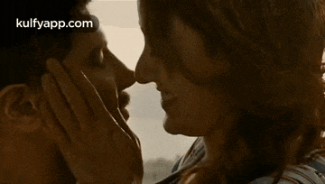 a man and a woman are kissing with their hands on each other 's faces .