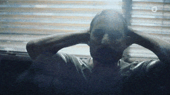 a man sitting in front of a window with his hands on his head