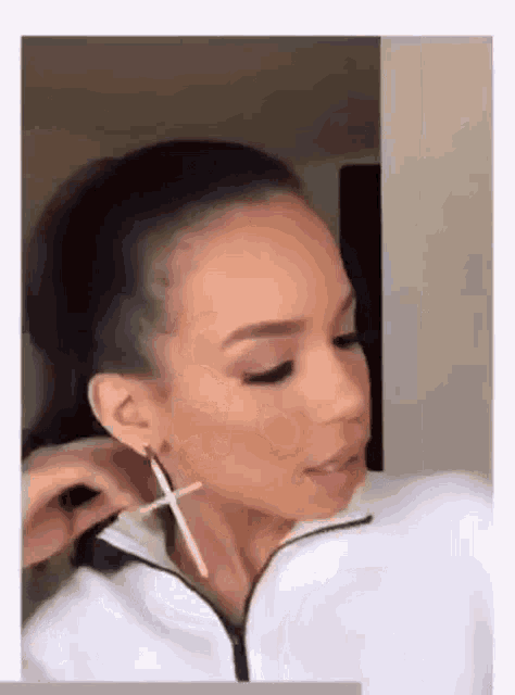 a woman wearing a pair of earrings with a cross on it .