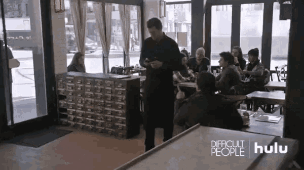 a group of people are sitting at tables in a restaurant with a sign that says difficult people on it