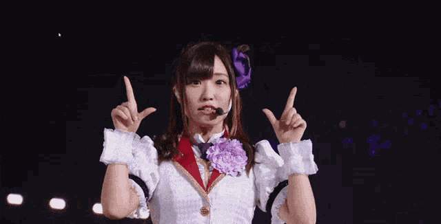 a girl with a microphone on her head giving a thumbs up