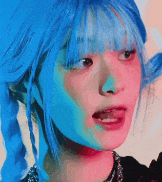 a close up of a girl with blue hair sticking out her tongue