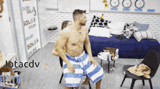 a man in a blue and white striped towel is dancing in a room with a sign that says solos solos solos