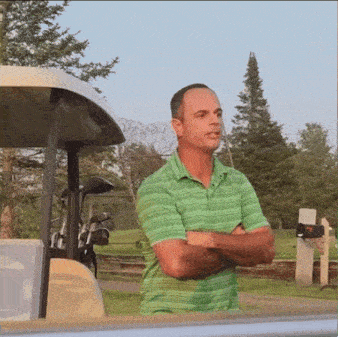 a man in a green shirt stands next to a golf cart