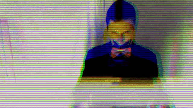 a man in a suit and bow tie is standing in front of a wall with a colorful background .