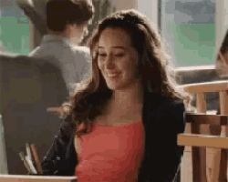 a woman in a red top and black jacket is sitting at a table in a restaurant .