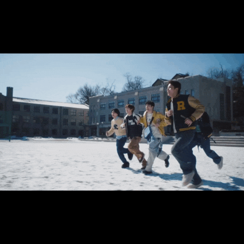 a group of people running in the snow with one wearing a jacket that says r on it