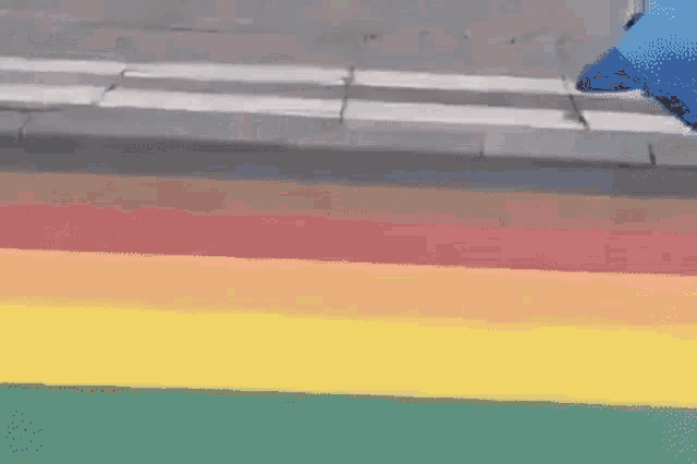a man is walking across a crosswalk with a rainbow painted on the sidewalk .