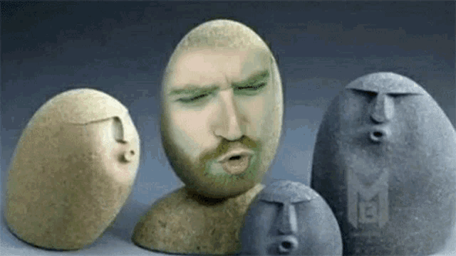 a group of rocks with faces carved into them are sitting on top of each other on a table .