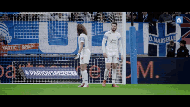 two soccer players on a field with a parions sport banner in the background