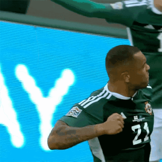 a soccer player in a green jersey with the number 21 on it