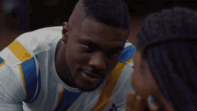 a man in a blue and yellow striped shirt looks at another man