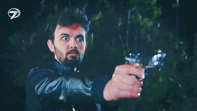 a man is pointing a gun at the camera with a letter p in the background