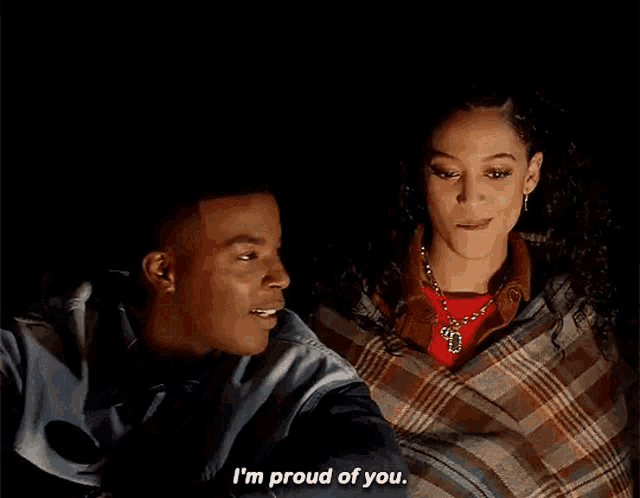 a man and a woman are wrapped in a plaid blanket and the woman says i 'm proud of you