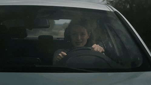 a woman is smiling while driving a car with a ring on her finger