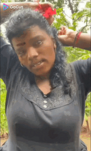 a woman is holding a flower in her hair while wearing a black shirt .