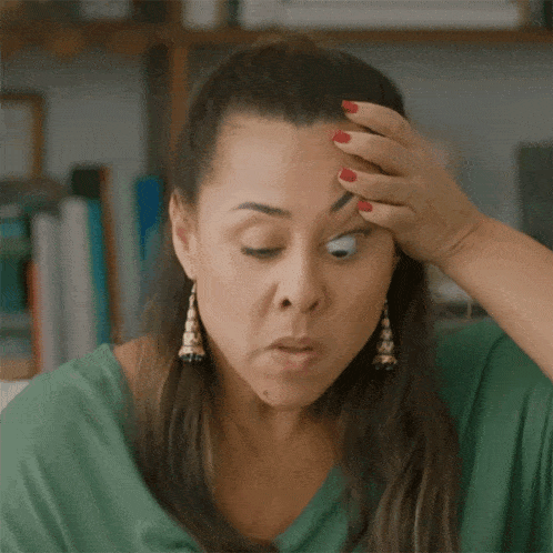 a woman with red nails holds her hand to her forehead while making a funny face