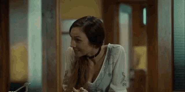 a woman wearing a choker is smiling and looking at the camera in a room .