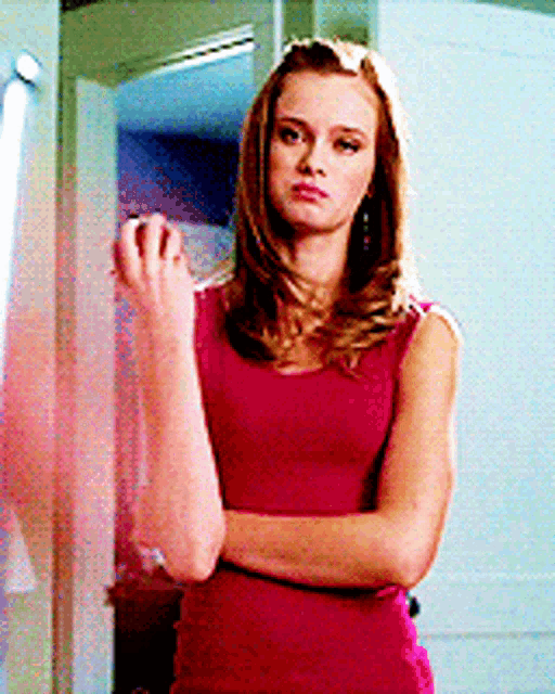 a woman in a pink tank top is standing in front of a mirror