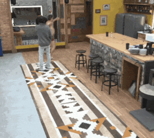 a man standing on a rug that says ' eee ' on it in a kitchen