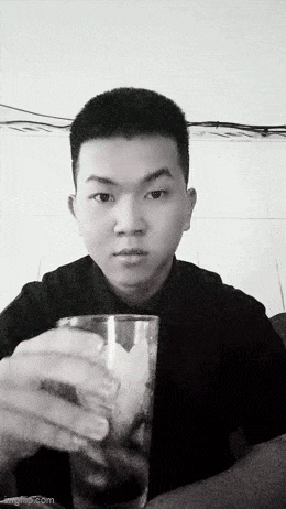 a black and white photo of a man holding a glass of water .