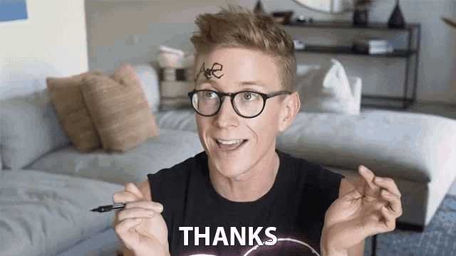 a man wearing glasses and a black shirt with the word thanks on it