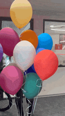 a bunch of colorful balloons are being held up by a person