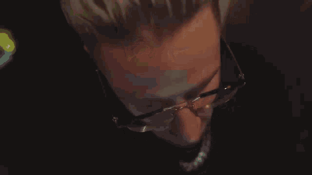 a man wearing glasses and a black shirt with the word wo on it