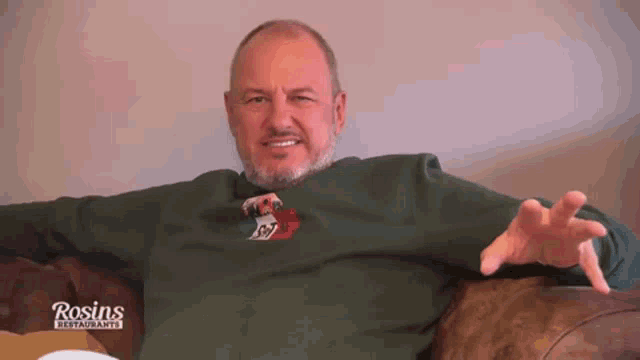 a man sitting on a couch wearing a rosin 's restaurant shirt