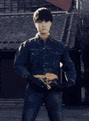 a young man in a denim jacket is holding a wrench in his hand
