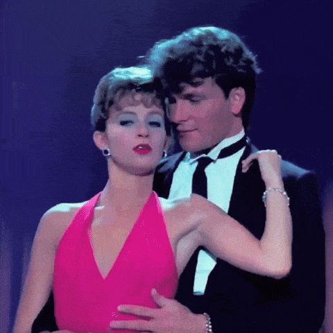 a man in a tuxedo is holding a woman in a pink dress