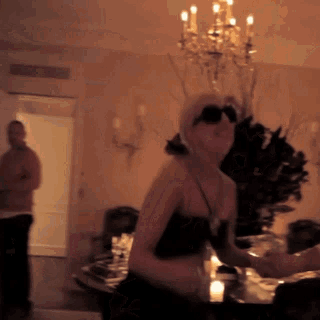 a woman wearing sunglasses is dancing in a room