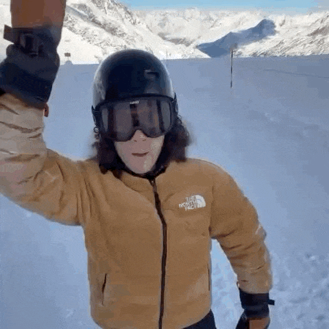 a man wearing a helmet , goggles and gloves is standing in the snow .