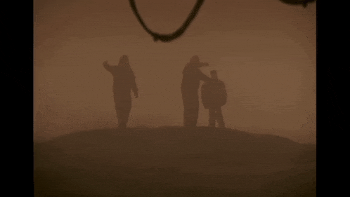 three people standing on top of a hill in the fog .